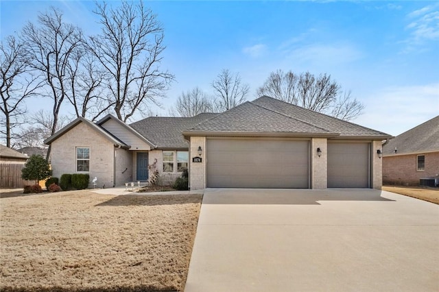 ranch-style house featuring brick siding, an attached garage, a shingled roof, cooling unit, and driveway