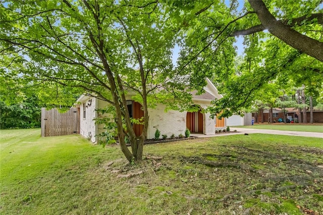 view of front of property featuring brick siding, fence, concrete driveway, a front yard, and an attached garage