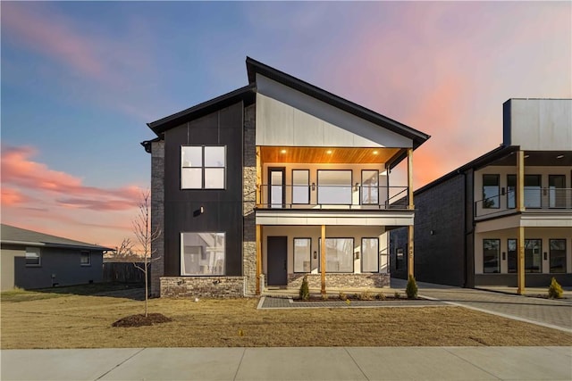 contemporary home with a balcony, decorative driveway, and stone siding