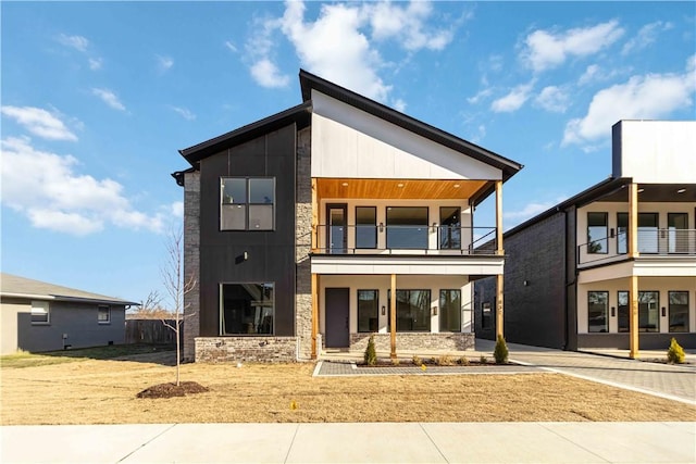 contemporary house featuring stone siding, driveway, and a balcony