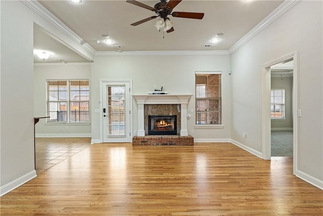 unfurnished living room with crown molding, a fireplace, light wood-style floors, and baseboards