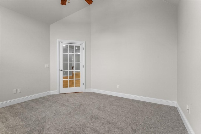 carpeted spare room featuring lofted ceiling, baseboards, and ceiling fan