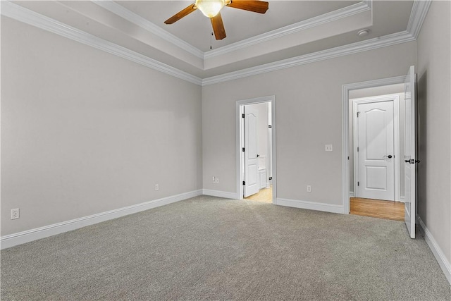 empty room with light carpet, baseboards, crown molding, and a tray ceiling