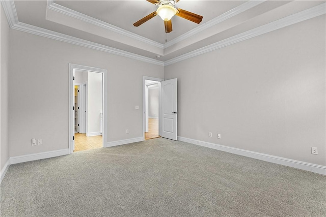 unfurnished bedroom with light colored carpet, baseboards, a tray ceiling, and ornamental molding