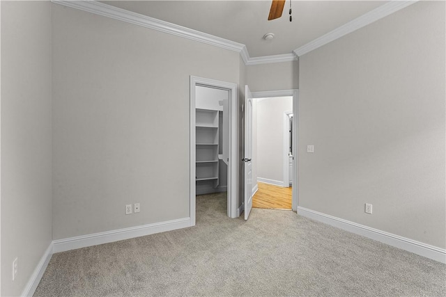 unfurnished bedroom featuring a walk in closet, crown molding, carpet flooring, and baseboards