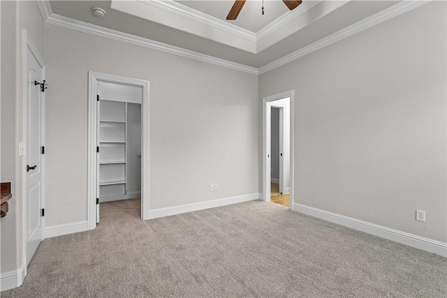 unfurnished bedroom with baseboards, carpet floors, a spacious closet, and crown molding