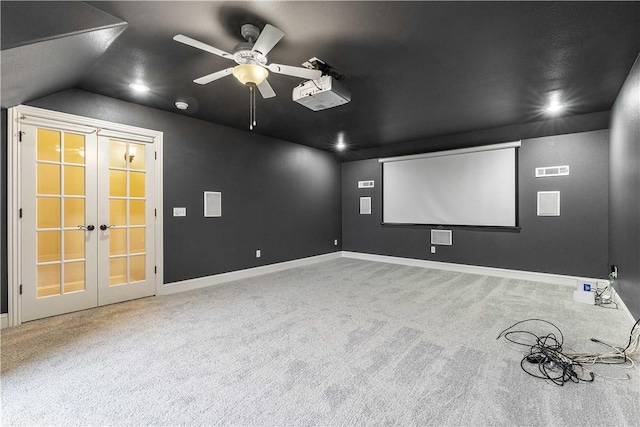 carpeted home theater room with visible vents, a ceiling fan, french doors, baseboards, and vaulted ceiling