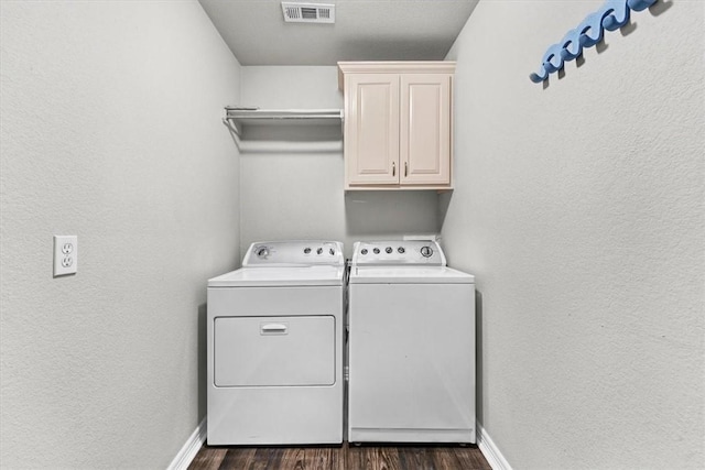 clothes washing area featuring baseboards, visible vents, dark wood finished floors, cabinet space, and washer and clothes dryer