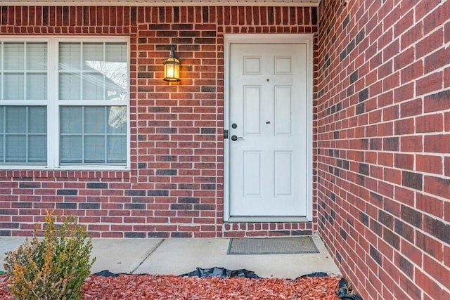 view of exterior entry with brick siding and crawl space