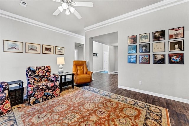 sitting room with visible vents, ornamental molding, wood finished floors, baseboards, and ceiling fan