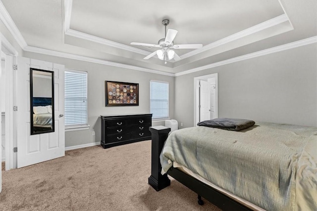 carpeted bedroom featuring a tray ceiling, baseboards, ceiling fan, and crown molding