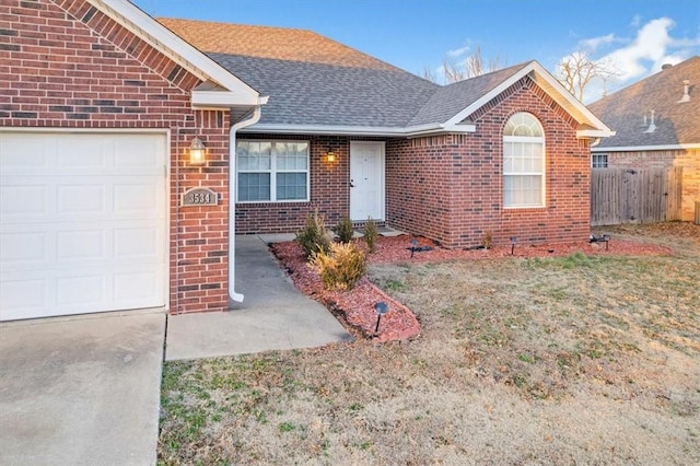 ranch-style home with brick siding, a shingled roof, a garage, and fence