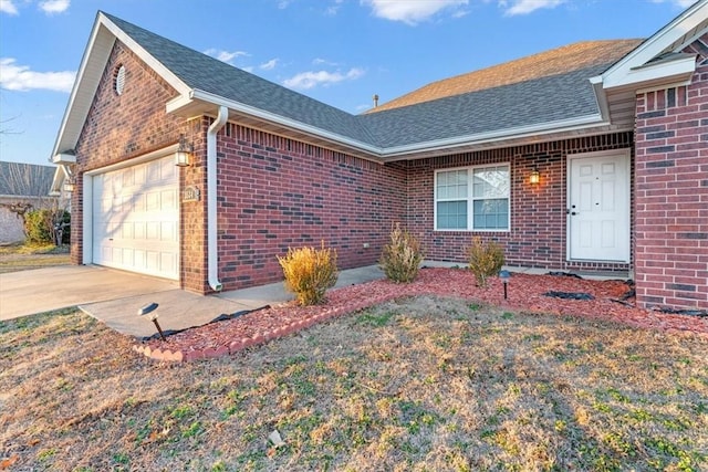 view of front of property featuring a garage, brick siding, roof with shingles, and driveway