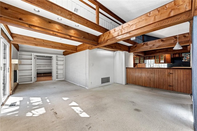 interior space with beam ceiling, carpet, and visible vents