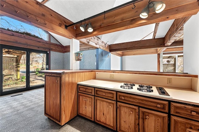 kitchen featuring visible vents, white gas stovetop, lofted ceiling with beams, light countertops, and light carpet