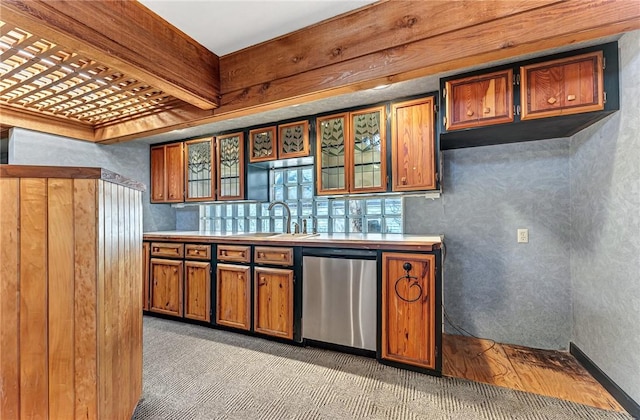 kitchen with brown cabinetry, dishwasher, light countertops, and a sink