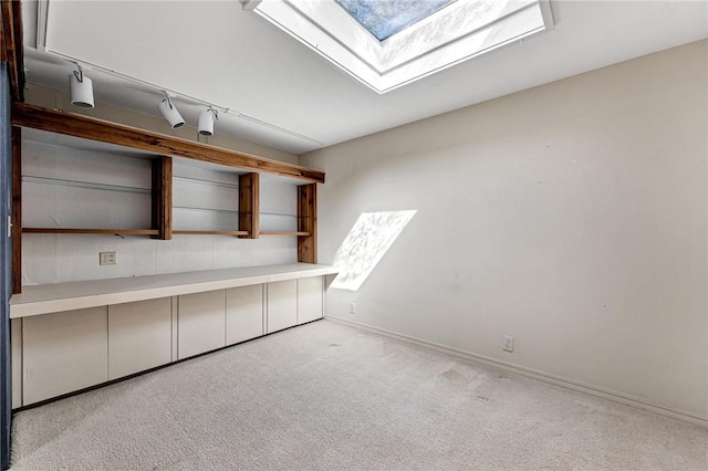 carpeted spare room featuring rail lighting, a skylight, and baseboards