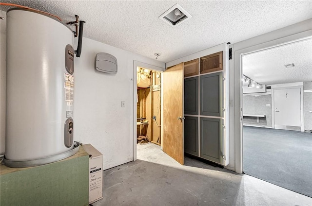 interior space with a textured ceiling, unfinished concrete flooring, visible vents, and electric water heater