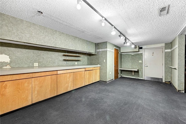 kitchen featuring brown cabinetry, visible vents, light countertops, track lighting, and a textured ceiling