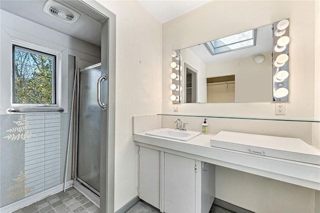 full bath featuring vanity, baseboards, visible vents, a skylight, and a stall shower