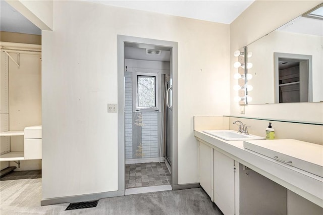 bathroom featuring a shower with shower door, visible vents, baseboards, and vanity