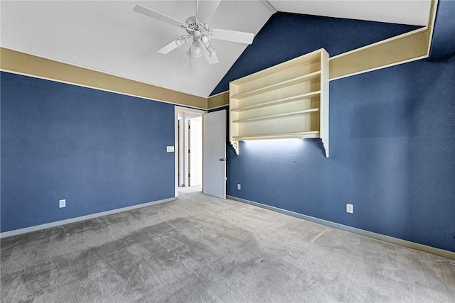 empty room featuring lofted ceiling, carpet flooring, baseboards, and ceiling fan