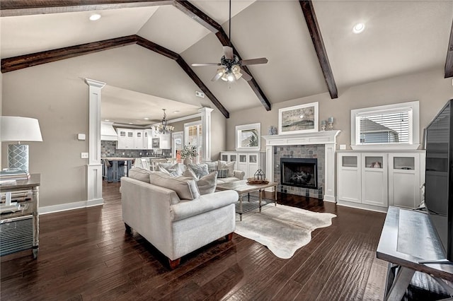 living room featuring a tiled fireplace, beamed ceiling, dark wood finished floors, and a wealth of natural light