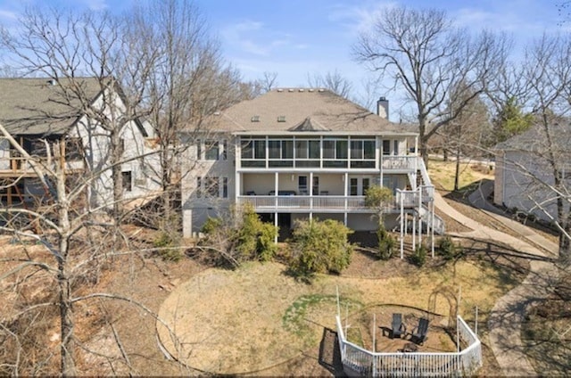 rear view of property with a wooden deck, a chimney, stairs, and a sunroom