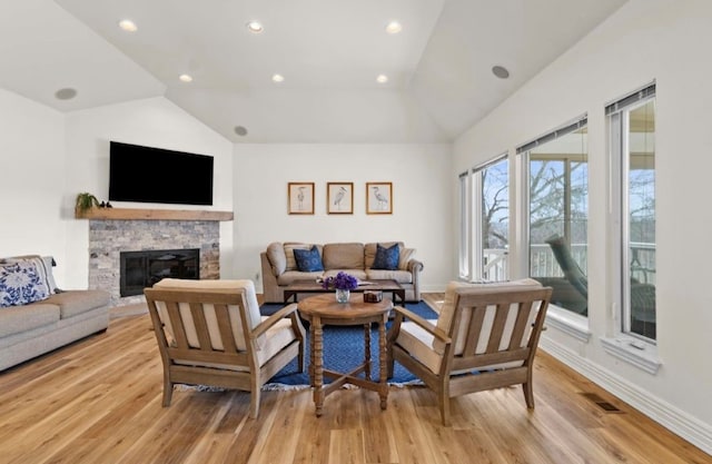 living room with light wood-type flooring, lofted ceiling, and a fireplace