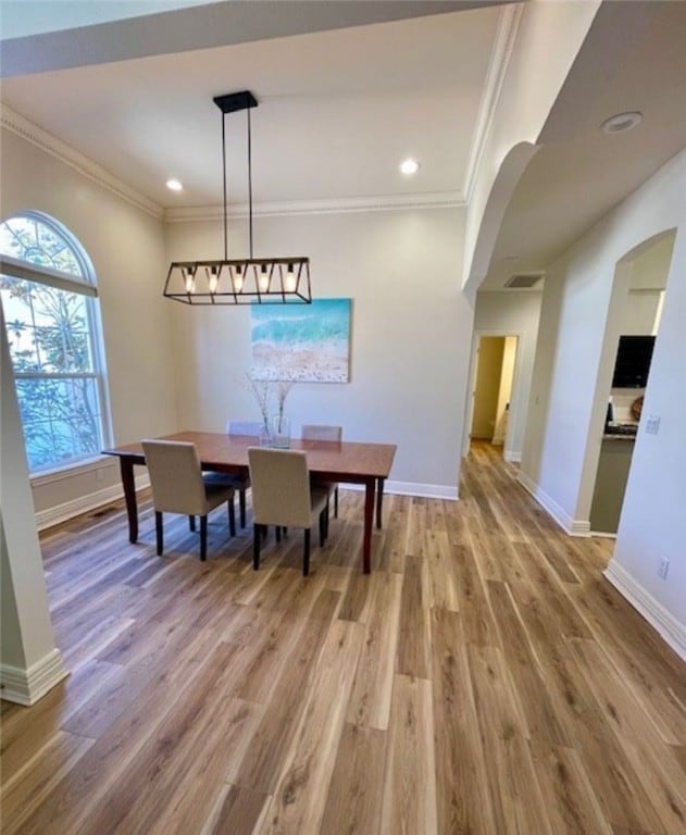 dining room with crown molding, wood finished floors, and baseboards