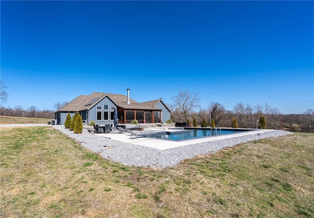 outdoor pool with a patio, a lawn, and a sunroom