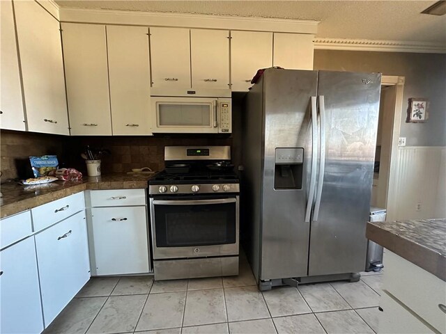 kitchen with light tile patterned floors, dark countertops, appliances with stainless steel finishes, and white cabinets