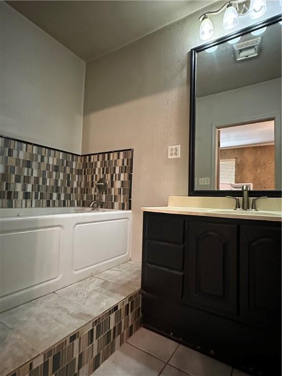 bathroom with vanity, tile patterned floors, and a bath