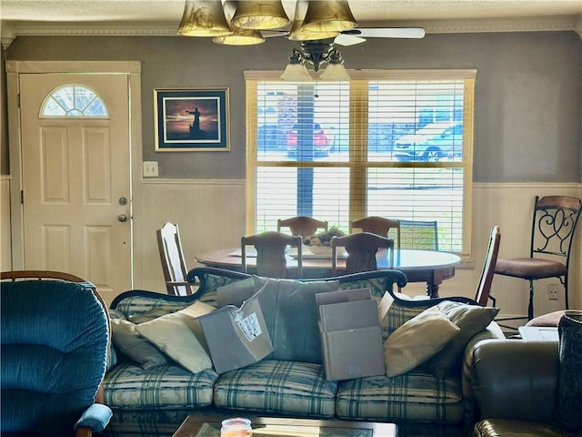 living area with a wainscoted wall and a ceiling fan