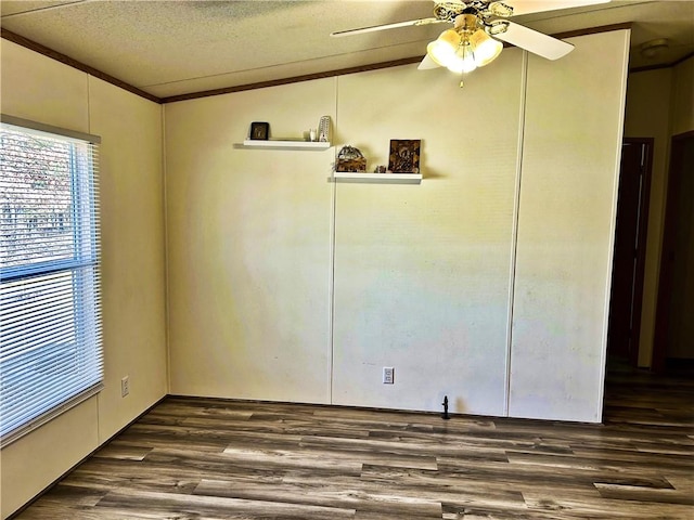 unfurnished room with crown molding, vaulted ceiling, dark wood-style floors, a textured ceiling, and a ceiling fan