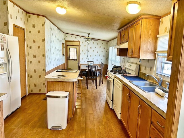 kitchen featuring wallpapered walls, white appliances, a textured ceiling, and a sink