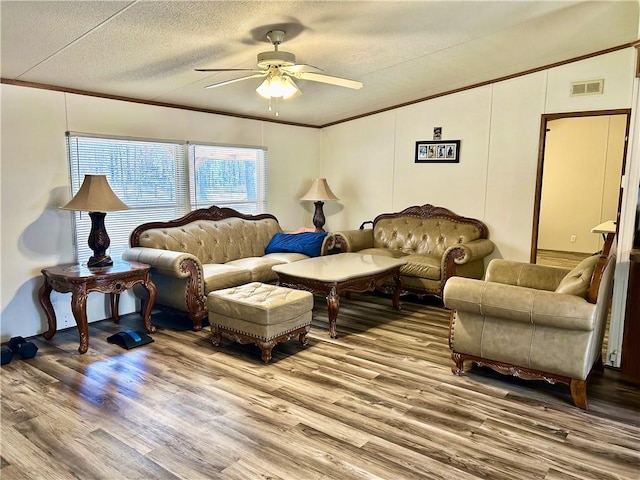 living area featuring visible vents, crown molding, wood finished floors, a textured ceiling, and a ceiling fan