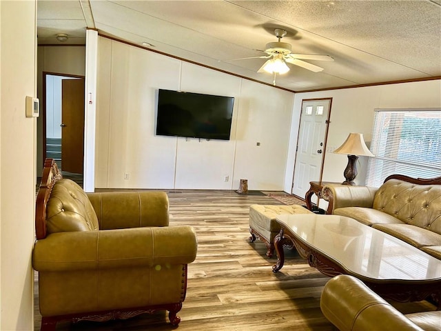 living area featuring ceiling fan, a textured ceiling, wood finished floors, and crown molding