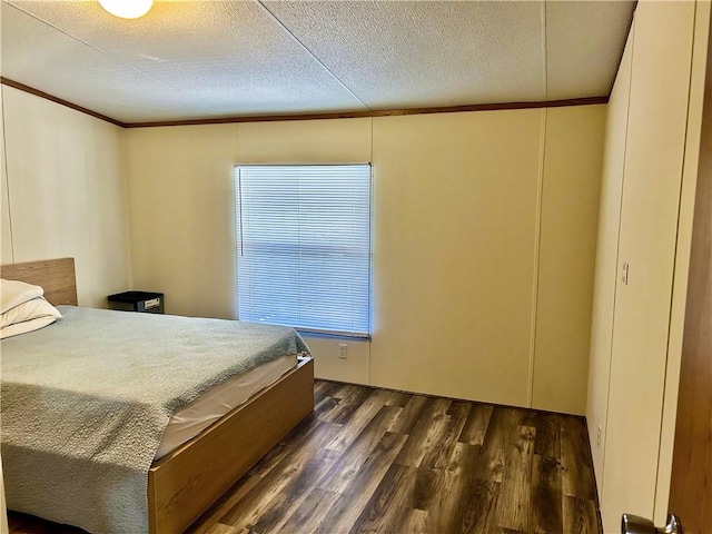 bedroom with dark wood-style floors, a textured ceiling, and ornamental molding