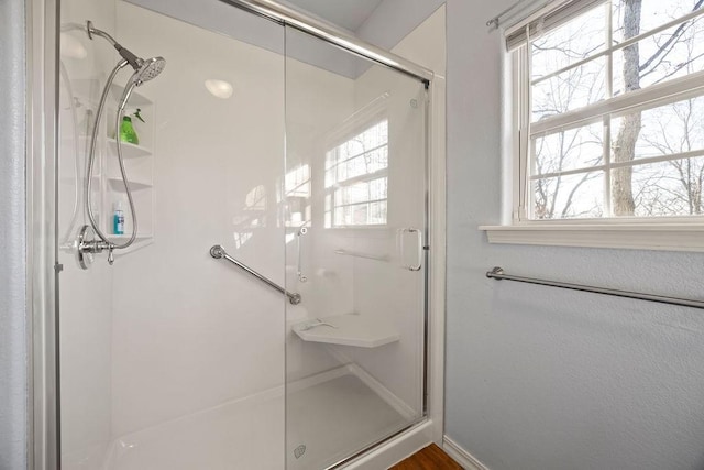 full bathroom with a healthy amount of sunlight, a stall shower, and baseboards