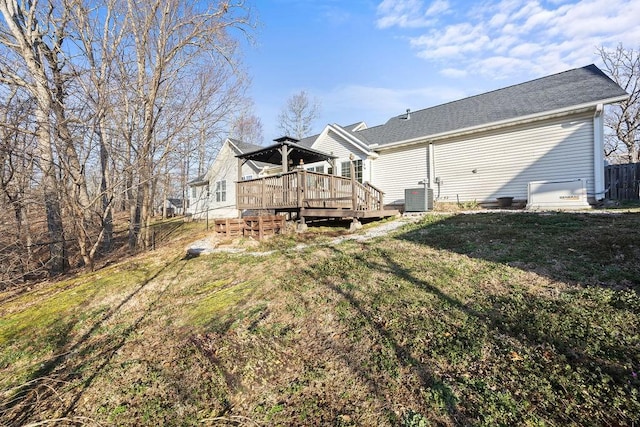 rear view of property with a deck, cooling unit, and a lawn