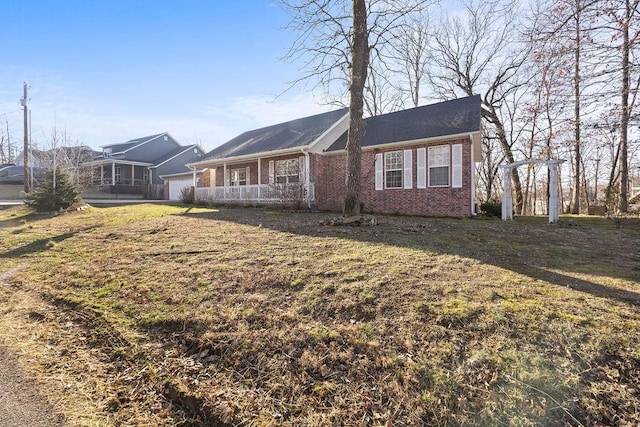 view of front of property featuring brick siding, covered porch, an attached garage, and a front lawn