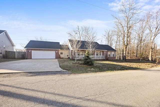 single story home with driveway, fence, covered porch, a garage, and brick siding