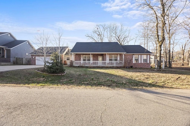 ranch-style home featuring a front lawn, driveway, a porch, a garage, and brick siding