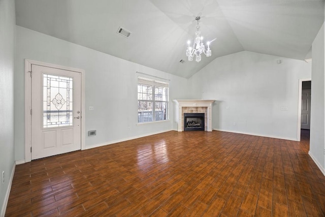 unfurnished living room featuring visible vents, lofted ceiling, a fireplace, wood finished floors, and a notable chandelier