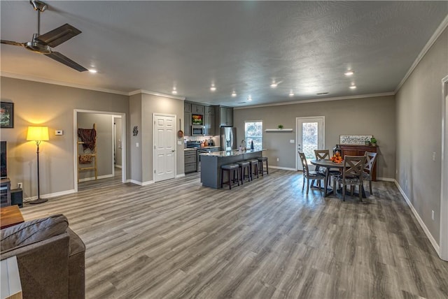 dining area featuring a ceiling fan, wood finished floors, baseboards, recessed lighting, and ornamental molding