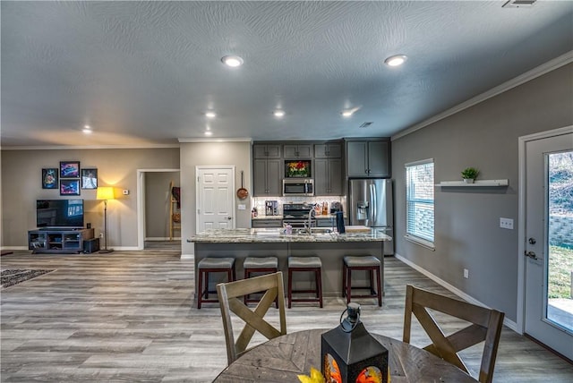 kitchen featuring a breakfast bar, light wood-type flooring, backsplash, and stainless steel appliances