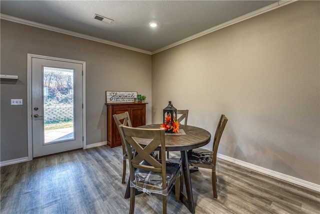 dining area featuring crown molding, wood finished floors, visible vents, and baseboards