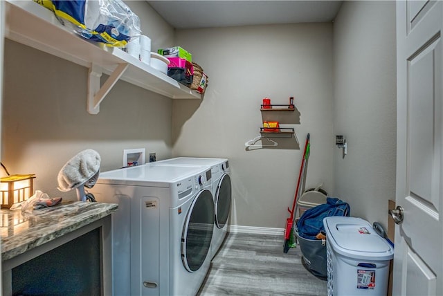 clothes washing area featuring baseboards, light wood-style floors, laundry area, and washing machine and clothes dryer