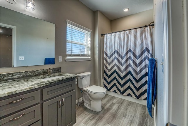 bathroom with toilet, vanity, a shower with curtain, and wood finished floors